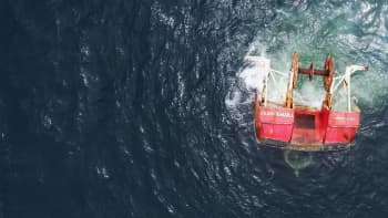 Photo of an old shrimp trawler, halfway submerged in the water. 