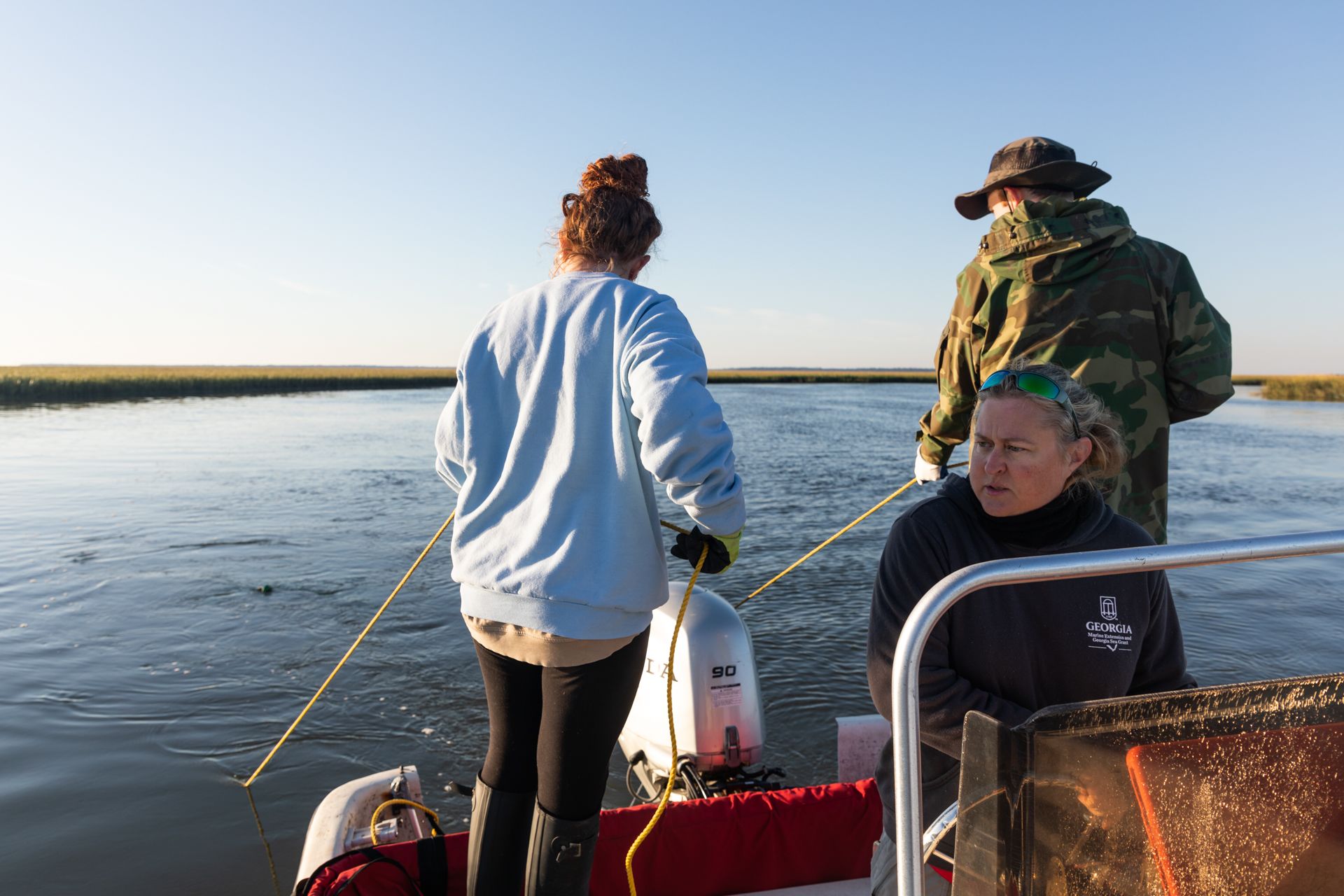 Marine Resource Specialist Lisa Gentit and student interns aboard a skiff, pulling a trawl net through the water