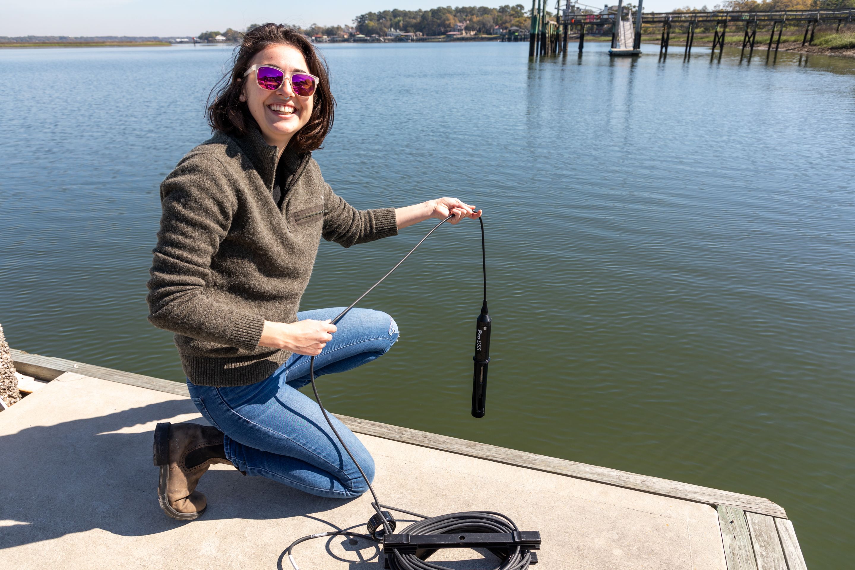 Mallory Mintz, kneeling on a dock, performing a plankton study.