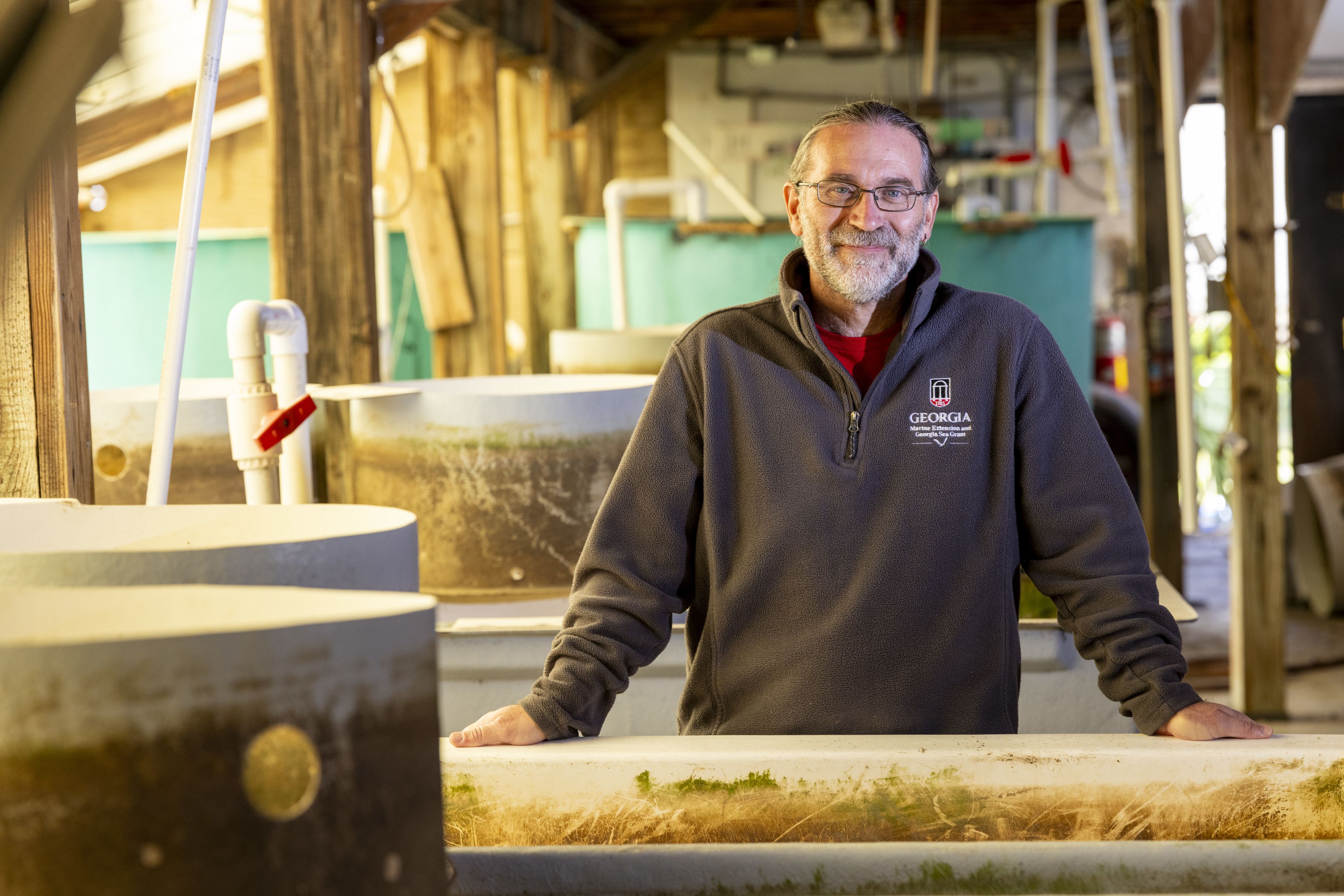 Photo of Tom Bliss, Director of the UGA Shellfish Research Lab, surrounded by oyster larval tanks