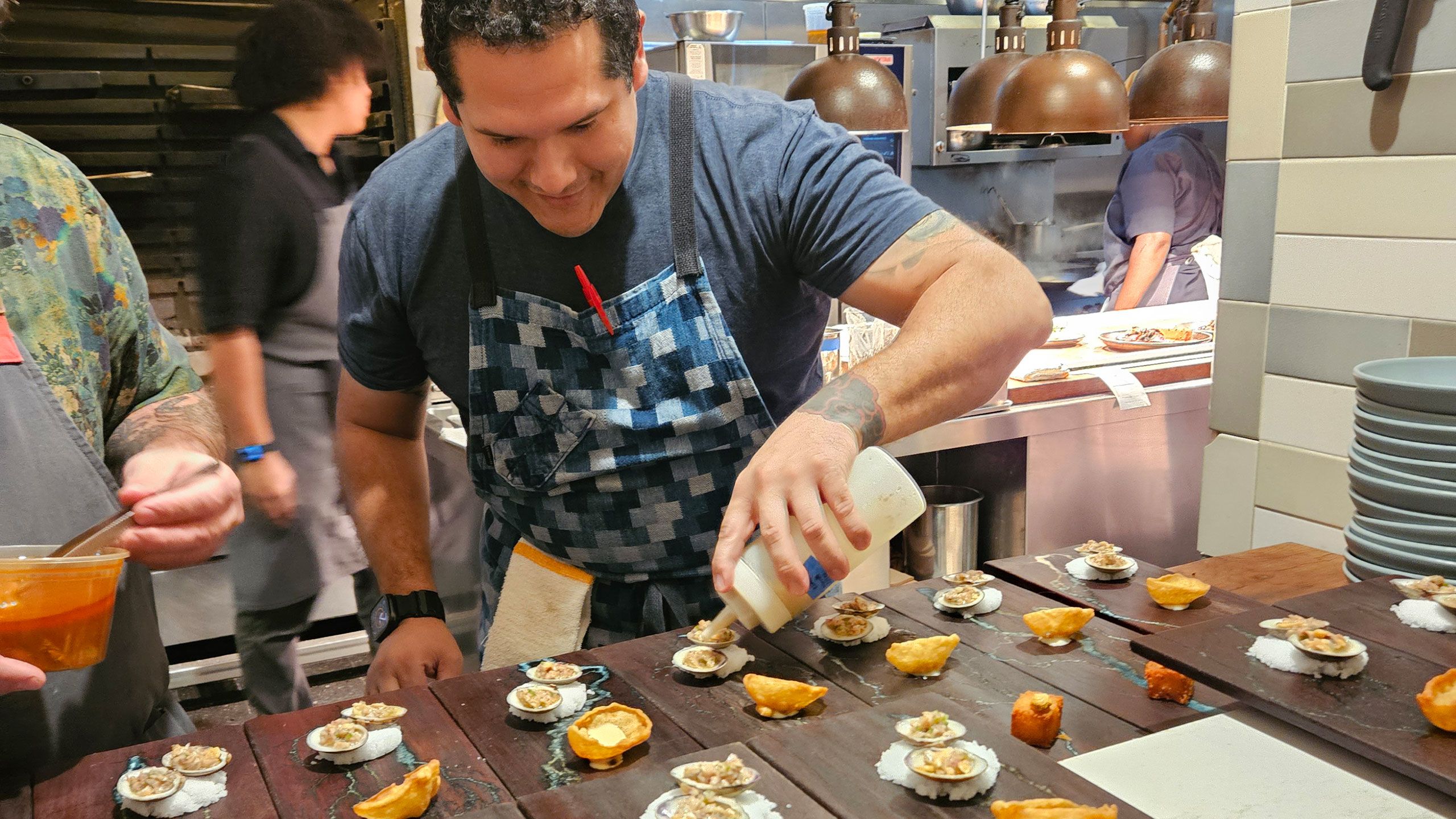 A chef prepares a series of seafood dishes in a commercial kitchen